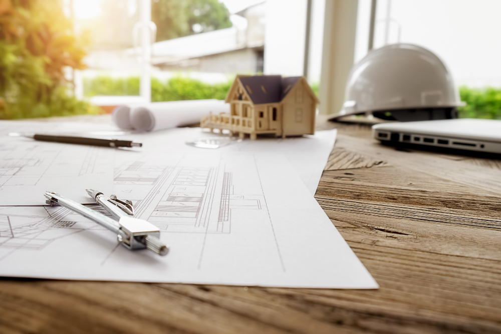 Deck remodeling project plans on a table with blueprints, model home, and contractor tools
