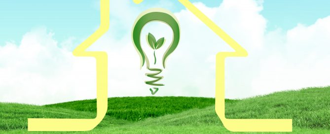Eco-friendly home remodel concept with green light bulb and house outline on grass.