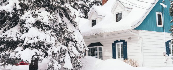 Snow-covered Maryland home showing winter conditions, heavy roof snow, and surrounding trees used to illustrate seasonal home improvement needs