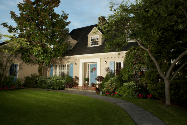 A Cape Cod style modular home featuring a steep roof, symmetrical blue shutters, and dormer windows, reflecting classic East Coast design.