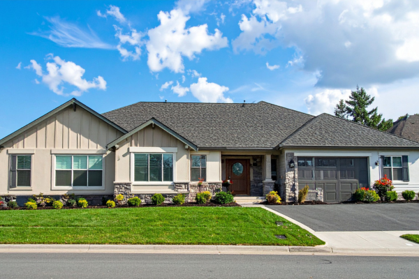 A single-story ranch style modular home with a wide front facade, stone wainscoting, and an attached garage.
