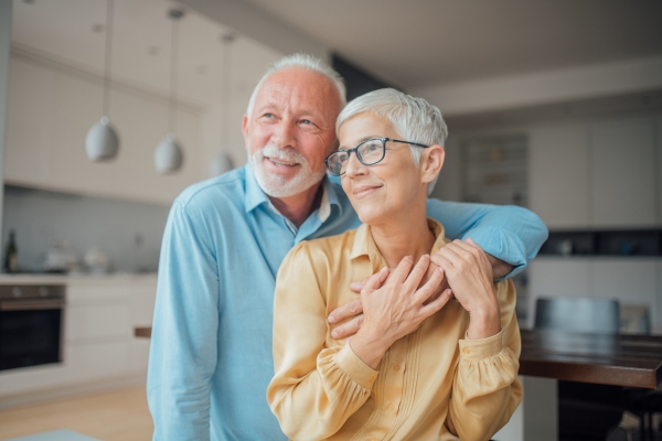 Aging in Place Contractor Near You in Maryland Older couple standing together in their kitchen at home, smiling as the man hugs the woman from behind