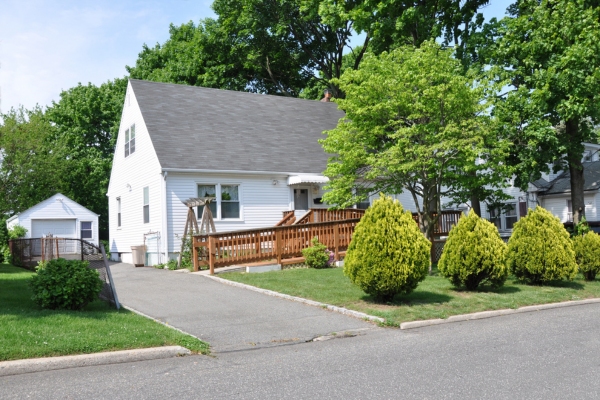 Home Entry Ramp for Aging in Place in Maryland White single-family home with a wooden wheelchair ramp leading to a zero-step front entry